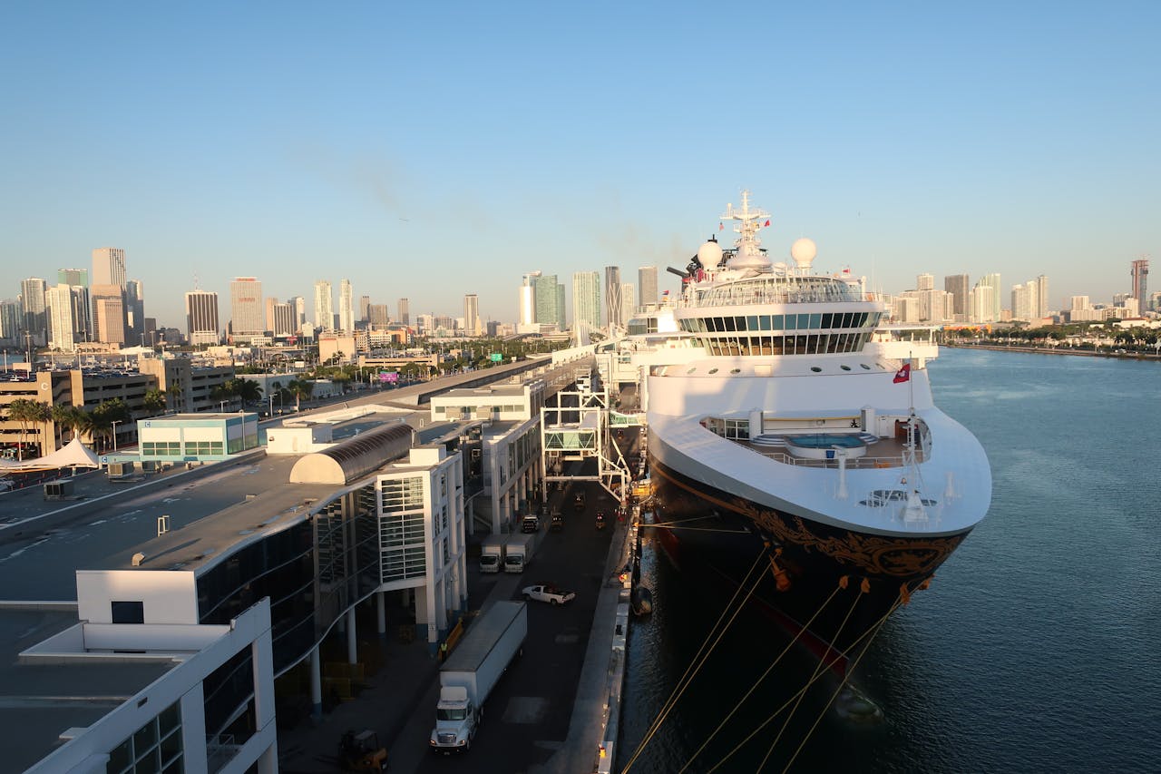 Aerial view of a cruise ship docked at Miami Beach port with a city skyline backdrop.
